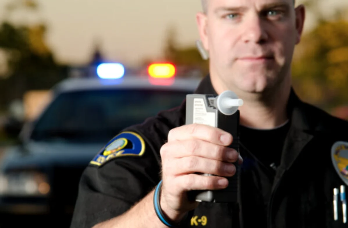 Police officier holding a breathalyzer gun